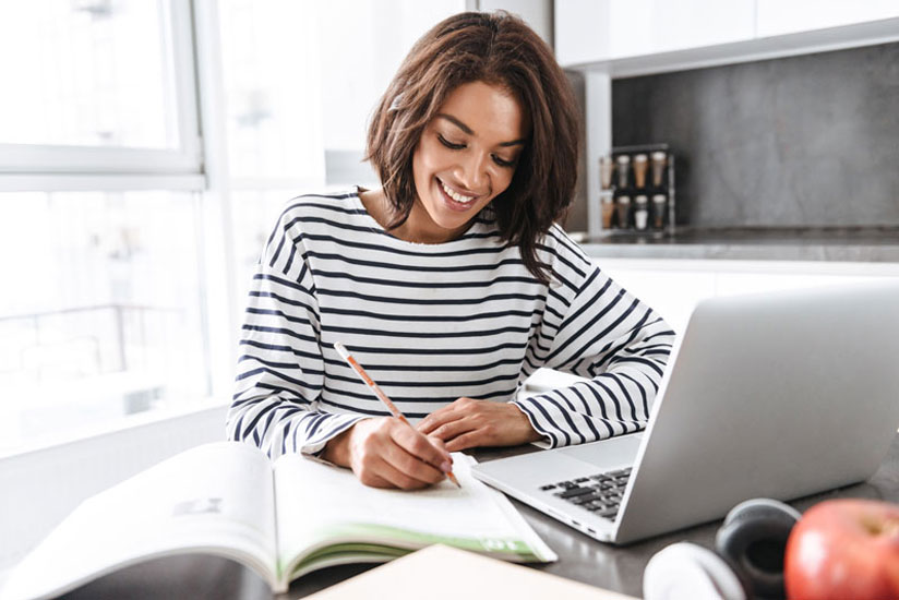 woman taking notes in front of laptop